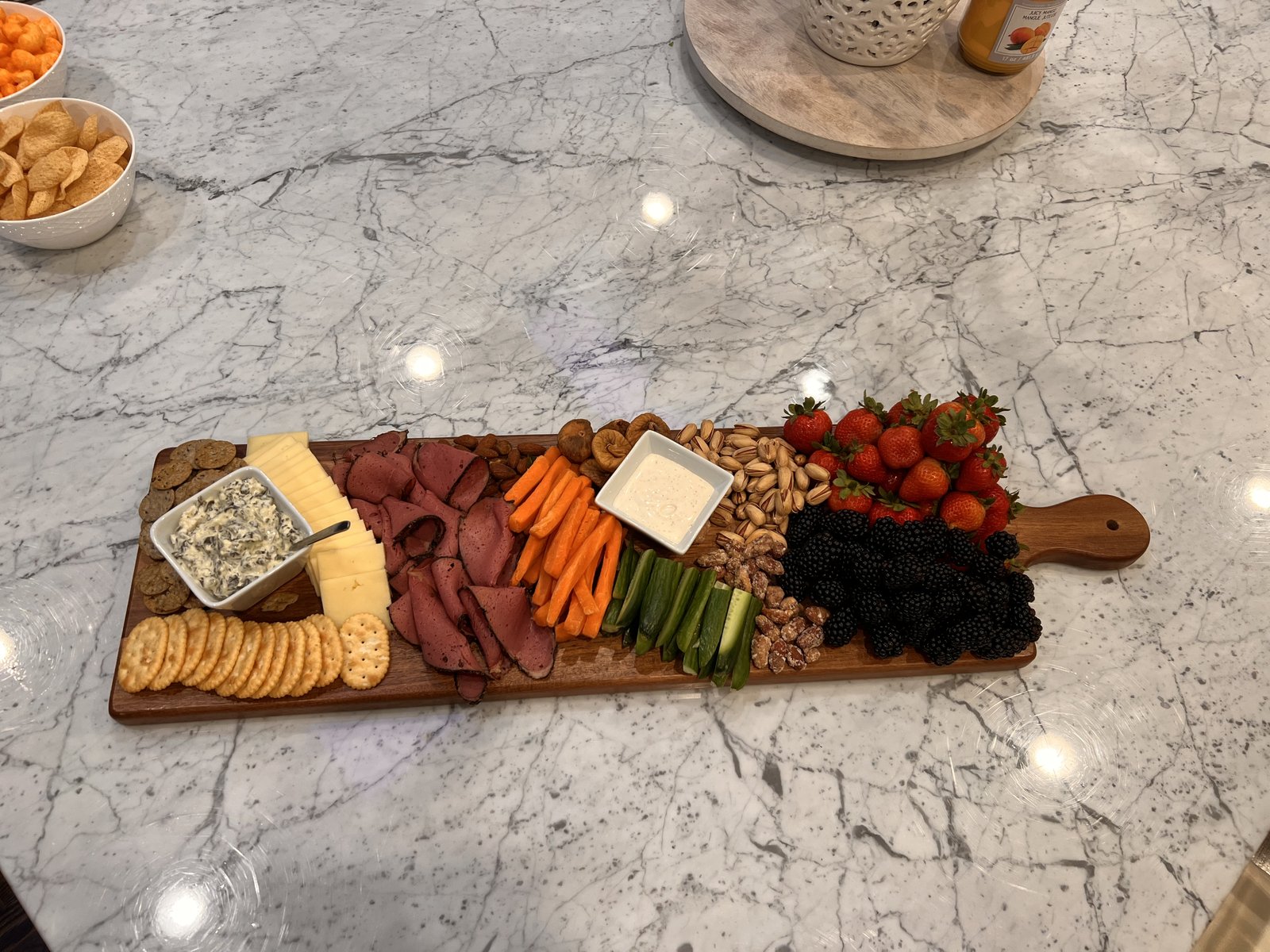 Long charcuterie table arrangement in a luxury kitchen with floral centerpiece