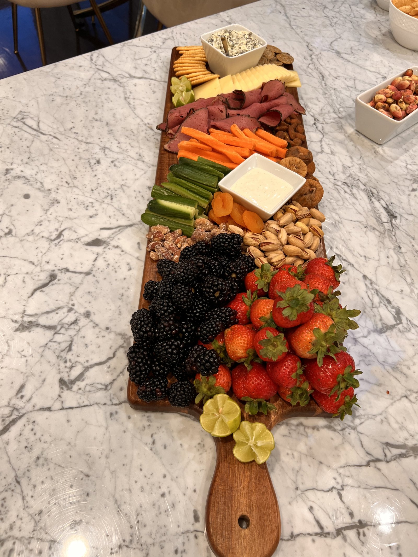 The Feast — kitchen island spread with abundant fruits, meats, and cheese